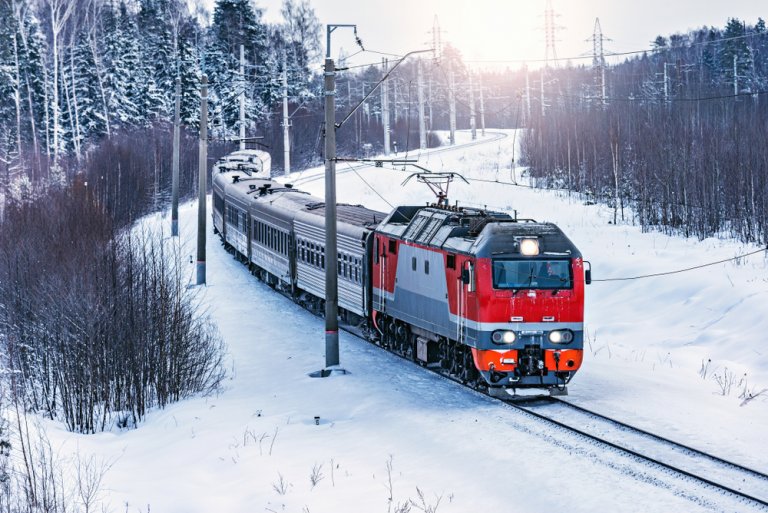 Пассажирский поезд РЖД едет зимой по заснеженному лесу