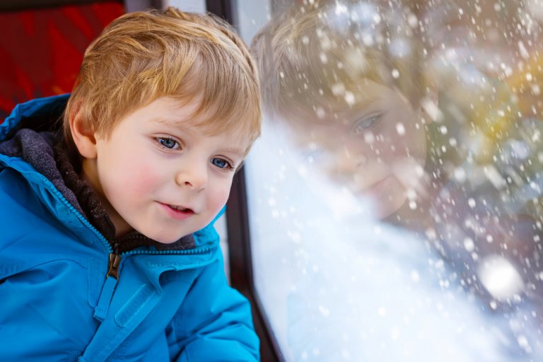 Мальчик едет в вагоне скоростного поезда зимой