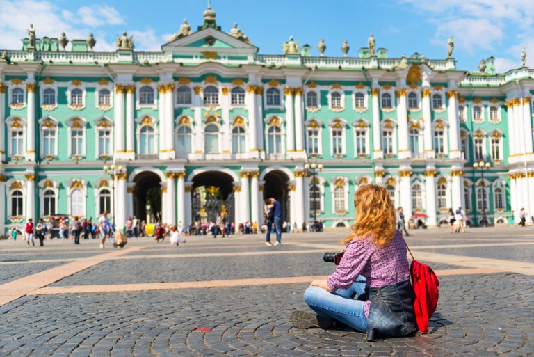 Туристка фотографирует Зимний дворец на дворцовой площади в Санкт-Петербурге