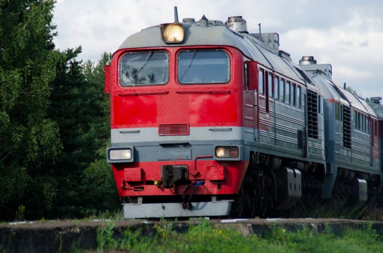 Пассажирский поезд РЖД едет летом по железной дороге в России. Скидка на плацкарт.
